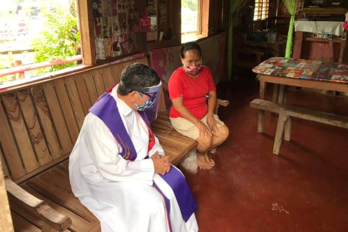 Pastor Amadeo Corpuz Alvero dari Paroki Santo Isidorus di Petani di McArthur, Leyte, mendengarkan pengakuan di dalam rumah penduduk desa, 22 April. FOTO PASTOR ALVERO