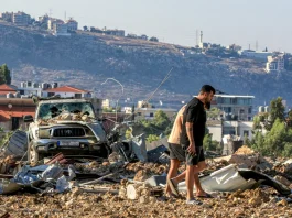 Dua orang berada di sekitar reruntuhan pasca serangan Israel di Lebanon.